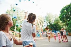 mangiare ghiaccio crema. allegro poco ragazza sua madre avere un' bene tempo nel il parco insieme vicino attrazioni foto