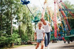 in esecuzione e giocando. allegro poco ragazza sua madre avere un' bene tempo nel il parco insieme vicino attrazioni foto