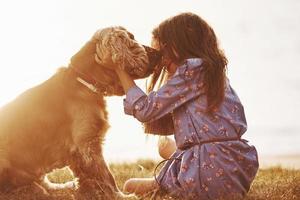 illuminato di bellissimo luce del sole. carino poco ragazza avere un' camminare con sua cane all'aperto a giorno foto