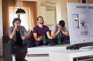 è un' sconfitta. triste tre amici Guardando calcio su tv a casa insieme foto