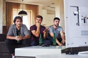 è un' sconfitta. triste tre amici Guardando calcio su tv a casa insieme foto