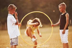 salto attraverso il cerchio fitness attrezzo. bambini avendo divertimento nel il campo foto