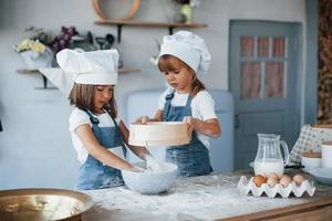 Usato setaccio. famiglia bambini nel bianca capocuoco uniforme preparazione cibo su il cucina foto