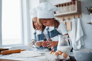 concentrandosi a cucinando. famiglia bambini nel bianca capocuoco uniforme preparazione cibo su il cucina foto