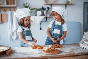 biscotti è pronto. famiglia bambini nel bianca capocuoco uniforme preparazione cibo su il cucina foto