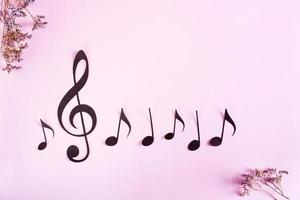 carta musicale chiave e Appunti nel un' riga e secco fiori su un' rosa sfondo. superiore Visualizza. foto