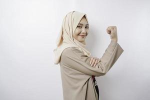 eccitato asiatico musulmano donna indossare un' hijab mostrando forte gesto di sollevamento sua braccia e muscoli sorridente con orgoglio foto