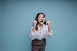 un' giovane asiatico donna con un' contento riuscito espressione indossare bianca camicia isolato di blu sfondo foto