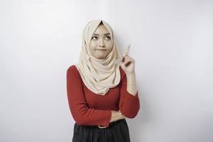 un' riflessivo giovane donna è indossare un' hijab e Tenere sua mento isolato di bianca sfondo foto