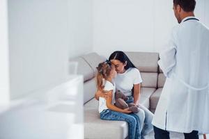 madre con sua carino figlia è visitare clinica. ascoltando per il medico foto