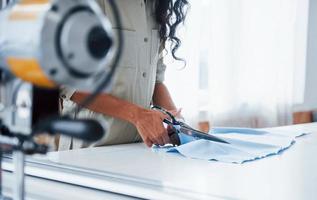 femmina lavoratore è nel il cucire fabbrica a giorno taglio stoffa con forbici foto