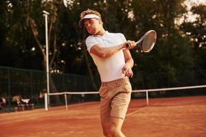 gioco nel azione. giovane tennis giocatore nel allegro Abiti è su il Tribunale all'aperto foto