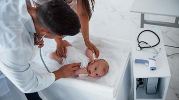 giovane pediatra è con poco bambino nel il clinica a giorno foto