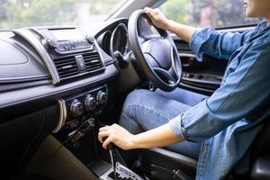 avvicinamento tiro di un' giovane donna guida un' auto con un automatico trasmissione. lei viaggi su vacanze foto