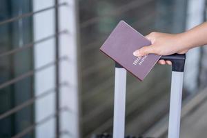 avvicinamento di giovane asiatico femmina turista Tenere passaporto e imbarco passaggio a aeroporto foto