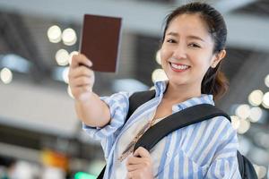 giovane asiatico femmina turista a il aeroporto su il fine settimana. lei era contento e mostrato sua passaporto nel mano foto