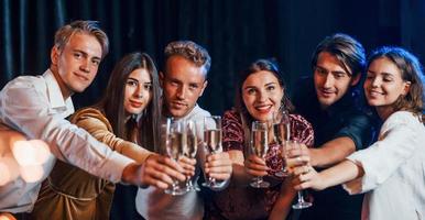 colpi occhiali. gruppo di allegro amici festeggiare nuovo anno in casa con bevande nel mani foto