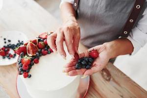 vicino su Visualizza di donna quello mette ciliegie su il dolce torta foto