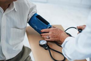 vicino su Visualizza. femmina medico usi tonometro per rendere sangue pressione misurazione per anziano uomo foto