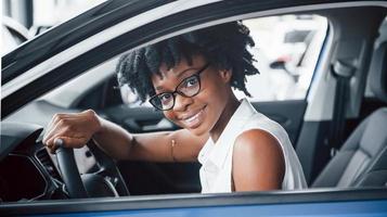 allegro Sorridi. giovane africano americano donna si siede dentro di nuovo moderno auto foto