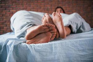 vicino su Visualizza di piedi di coppia quello dorme insieme nel il Camera da letto a mattina tempo foto