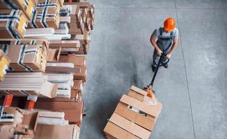 superiore Visualizza di maschio lavoratore nel magazzino con pallet camion foto