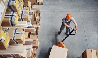 superiore Visualizza di maschio lavoratore nel magazzino con pallet camion foto