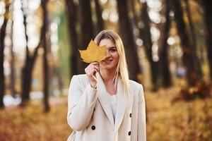 ritratto di giovane brunetta con foglia quello è nel autunno foresta a giorno foto