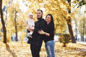 allegro famiglia avendo divertimento insieme con loro bambino nel bellissimo autunno parco foto