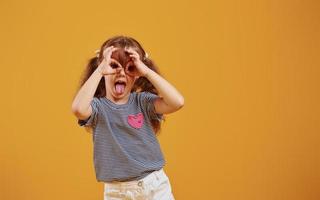 carino poco ragazza nel casuale Abiti avere divertimento nel il studio contro giallo sfondo foto