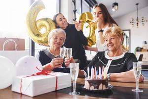 palloncini con numero 60. anziano donna con famiglia e amici festeggiare un' compleanno in casa foto