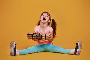 poco ragazza con esplosivo nel il studio contro giallo sfondo foto