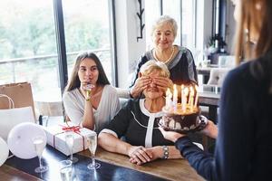 anziano donna con famiglia e amici festeggiare un' compleanno in casa foto