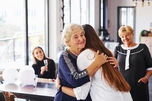 Abbracciare una persona ogni Altro. anziano donna con famiglia e amici festeggiare un' compleanno in casa foto