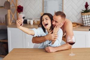 coppia insieme nel il cucina a mattina tempo con mobile Telefono foto