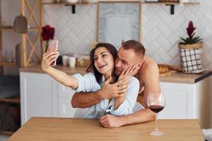 coppia insieme nel il cucina a mattina tempo con mobile Telefono foto