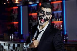 urlando per il telecamera. ritratto di uomo quello è su il tematico Halloween festa nel pauroso scheletro trucco e costume foto