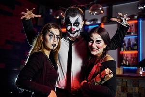 amici è su il tematico Halloween festa nel pauroso trucco e costumi avere divertimento e in posa per il telecamera insieme foto