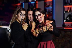 tre femmina amici è su il tematico Halloween festa nel pauroso trucco e costumi foto