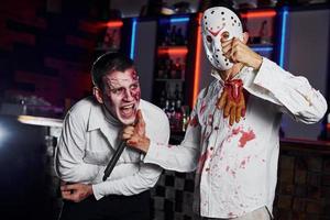 amici è su il tematico Halloween festa nel pauroso trucco e costumi di zombie foto