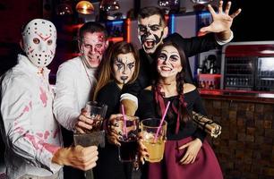 in posa per il telecamera. amici è su il tematico Halloween festa nel pauroso trucco e costumi foto