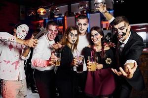 in posa per il telecamera. amici è su il tematico Halloween festa nel pauroso trucco e costumi foto