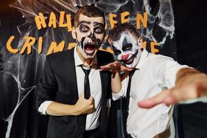 amici è su il tematico Halloween festa nel pauroso trucco e costumi urlando per il telecamera foto