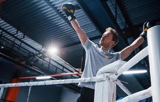 uomo nel protettivo guanti e nel bianca camicia festeggiare vittoria su boxe squillare foto