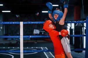 ritratto di Due giovane ragazzi nel protettivo guanti festeggiare vittoria su boxe squillare foto