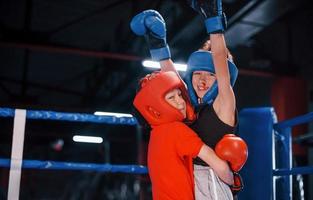 ritratto di Due giovane ragazzi nel protettivo guanti festeggiare vittoria su boxe squillare foto