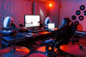 suono ingegnere Lavorando e miscelazione musica in casa nel il studio vicino tamburo kit foto