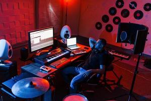 suono ingegnere Lavorando e miscelazione musica in casa nel il studio vicino tamburo kit foto