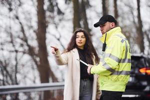 maschio polizia ufficiale nel verde uniforme parlando con femmina proprietario di il auto su il strada foto