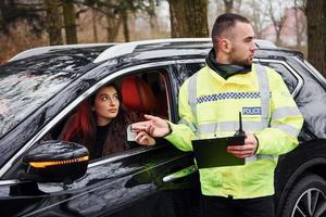 maschio polizia ufficiale nel verde uniforme prende corrompere a partire dal donna nel auto foto
